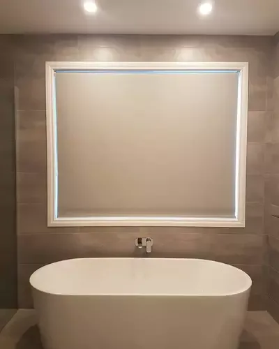 Bathroom with downlights and a lit mirror above a freestanding bath